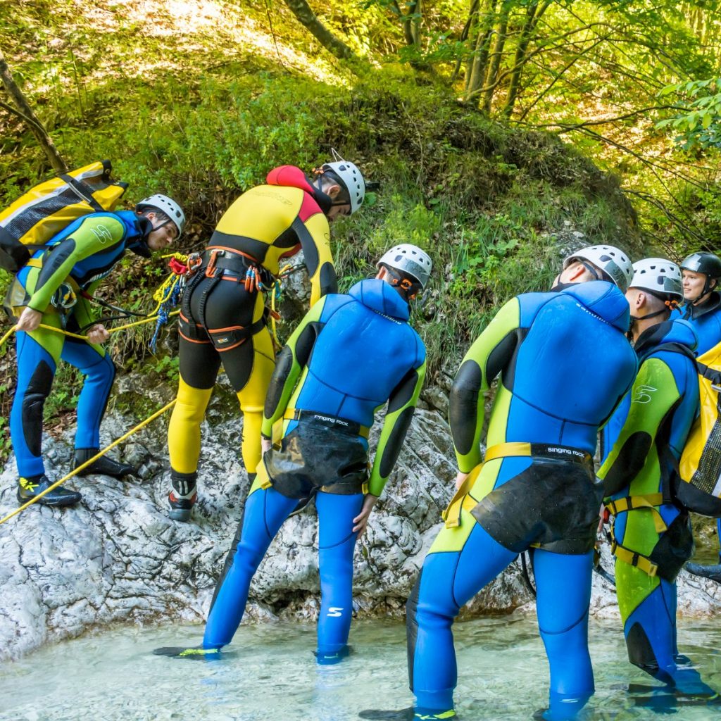 Canyoning guide Matej is teaching a group of canyoneers how to set up an anchor.