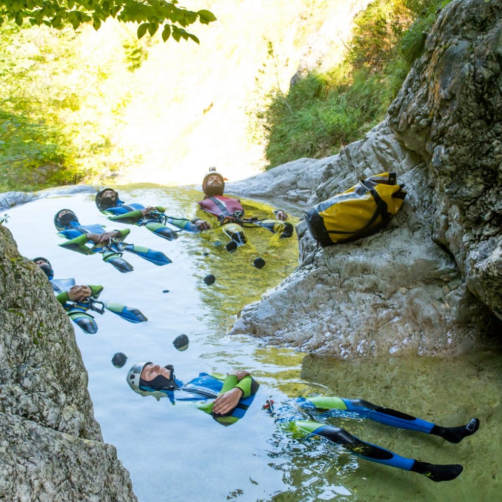 A group of people wearing wetsuits is doing floating meditation in a pond of water.