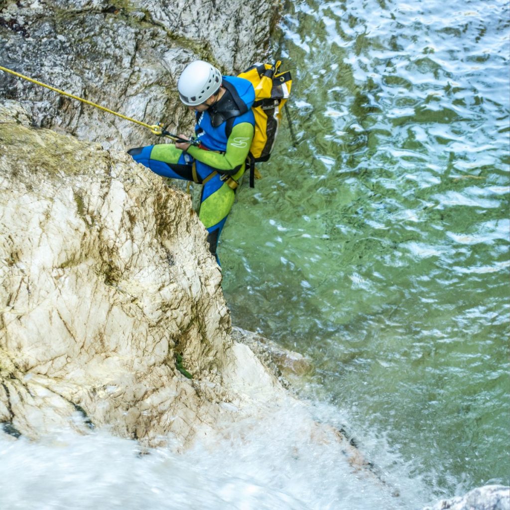 A man in a neoprene suit is learning how to become a Bovec canyoning guide.